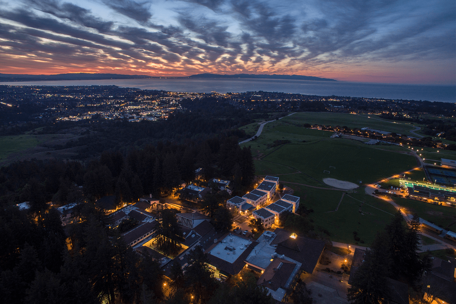 Drone shot of UCS campus at sunset with ocean at the horizon.