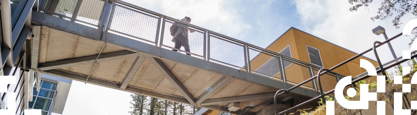 Student walking on a bridge with mesh metal sides
